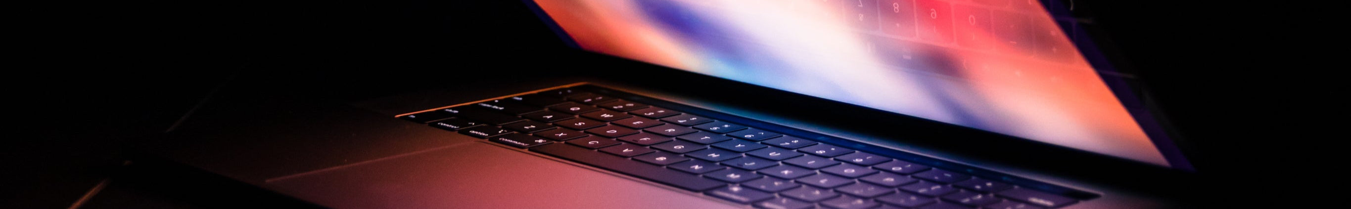 Laptop glowing in a dark workspace — the everyday tools behind Orchard's work